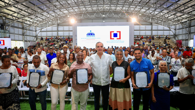 El presidente Luis Abinader junto a las familias beneficiadas con los certificados de títulos de propiedad. (Fuente Oficial). Inter News Service